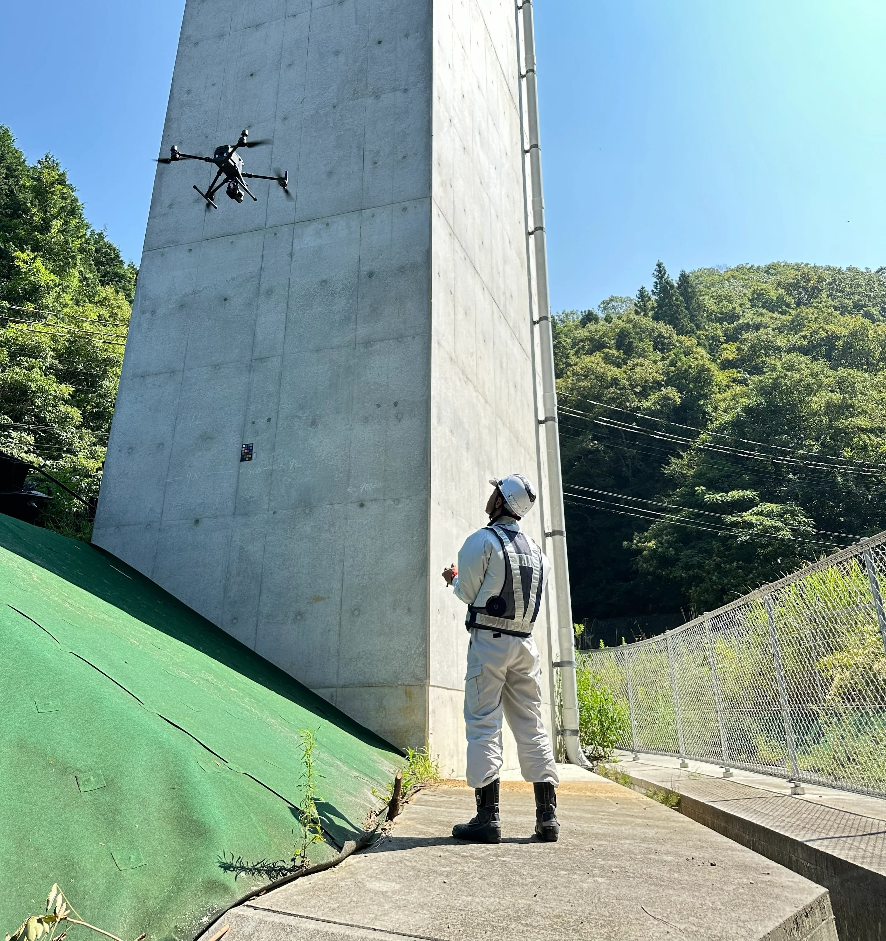 白い作業服の操縦者が橋脚点検用ドローンを操作する様子